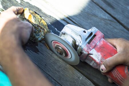 male hand cut the batu akik or natural gemstone rought with hand grinderの写真素材