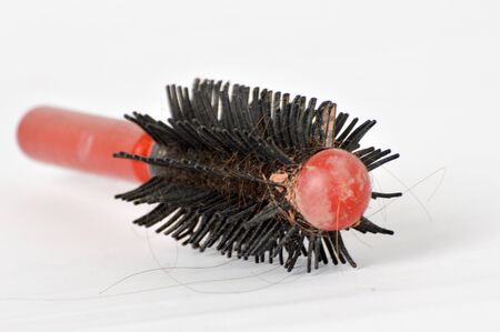 red comb with strand of hair losson white backgroundの写真素材