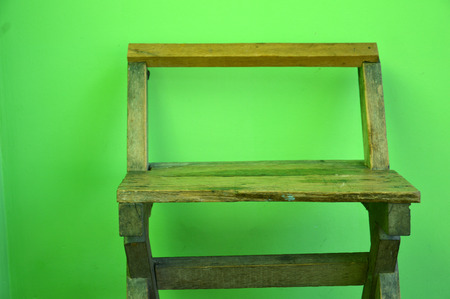 old used wooden chairs on the green wallの写真素材