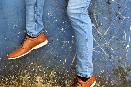 leather shoes with jeans on concrete wall