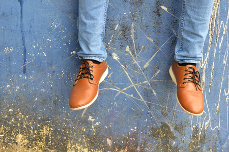 leather shoes with jeans on concrete wall