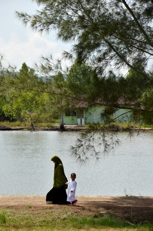 TARAKAN, INDONESIA - 30th MAY 2016 : Muslim boys with him mother by the poolのeditorial素材