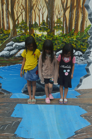 TARAKAN, INDONESIA - 5th August  2017 : the little girls pose on the three-dimensional mural painting on the cement wallのeditorial素材