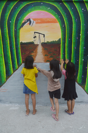 TARAKAN, INDONESIA - 5th August  2017 : the little girls pose on the three-dimensional mural painting on the cement wallのeditorial素材
