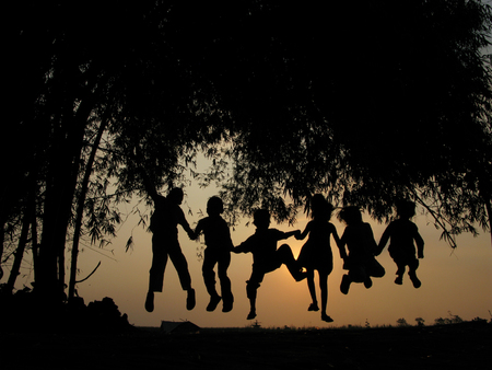 Natural silhouettes of children chatting and playing under a bamboo treeの写真素材