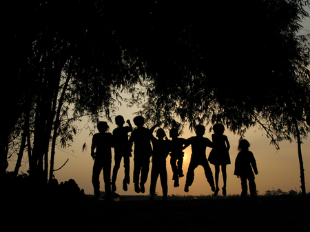 Natural silhouettes of children chatting and playing under a bamboo treeの写真素材