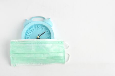surgical mask covering the alarm clock isolated on white background