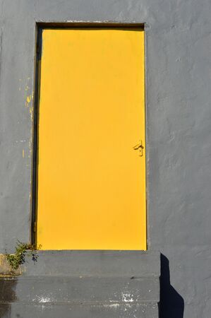 yellow iron door with gray cement wall