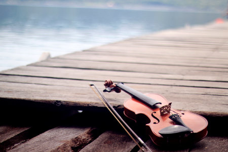 violin lying on a wooden plank bridgeの写真素材