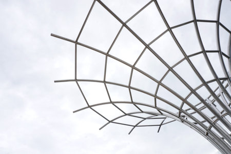 Abstract metal sculpture against a cloudy sky. Contemporary design with geometric patterns, ideal...