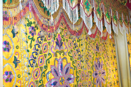 Experience the opulent beauty of this richly decorated yellow fabric. Intricate floral patterns and shimmering beaded trim create a luxurious, festive atmosphere perfect for celebrations.の写真素材