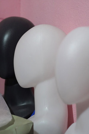 Abstract trio of mannequin heads in black, white against a pink wall. Perfect for retail, art,...