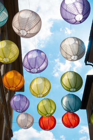 Lanterns of many colours hang in the German city of Wurzburg. Decorations are backlit against a blue sky in this street scene viewed from below - Vertical Imageの写真素材