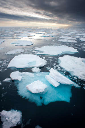 Northern Arctic ice floes are seen breaking up and melting leading into an atmospheric moody sky on the horizon.Climate crisis emergency and global warming.Imageの写真素材