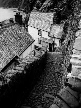 A coastal cottage in Devon built on the side of a hill has a cobbled path leading to it lined by man made stone walls.Cliffs and sea in background.Imageの写真素材