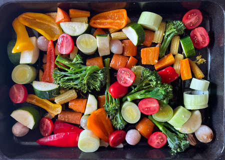 A tray of multi coloured uncooked sliced vegetables.Healthy vegan and vegetarian food for roasting in ovenの写真素材