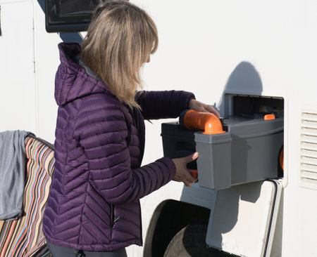 A lady motor homer moves the toilet cassette from her motorhome recreational vehicle locker,RVの写真素材