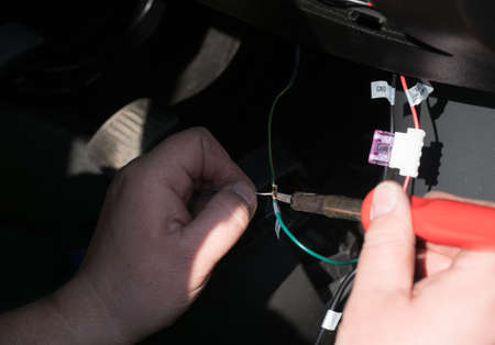 A pair of hands holding a soldering iron and wiring fixing wires togetherの写真素材