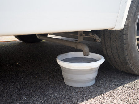 A collapsible bucket has ben placed under the waste pipe of a motorhome rcreational vehicle to collect grey water from the onboard waste tankの写真素材