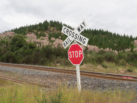 A red stop and railway crossing sign in wild landscape with rail track visible.New Zealandの写真素材