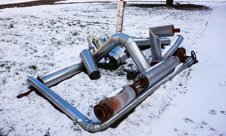 Discarded old insulated hot water pipe with valve on snowの写真素材