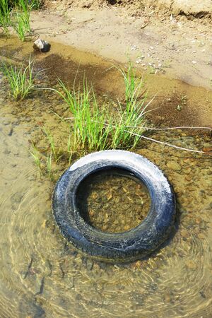 An old discarded tire thrown into a lakeの写真素材