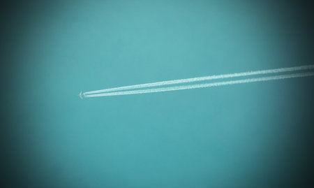 A flying plane in the sky leaves a white trail behindのeditorial素材