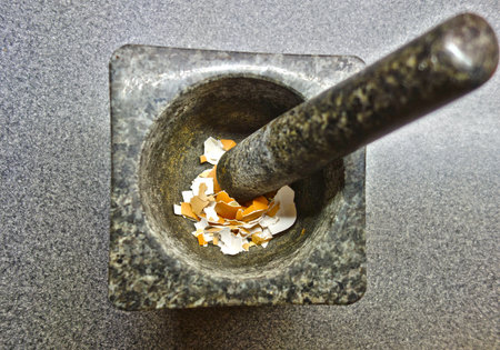 Crushed eggshells in a mortar made of massive natural graniteの写真素材