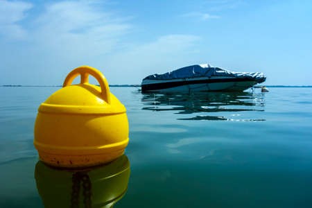 Floating buoy on the lake, in the background anchored motorboat in the recreation center