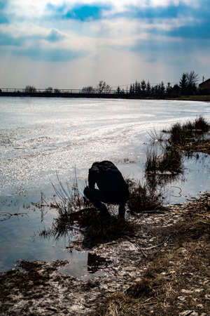 The photographer takes pictures by the pond in the winter in beautiful nature