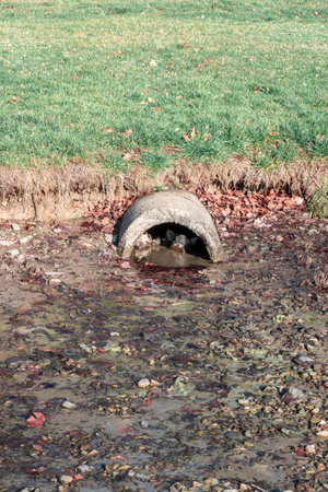 The damaged but functional sewage pipe drains rainwater into the lakeの写真素材