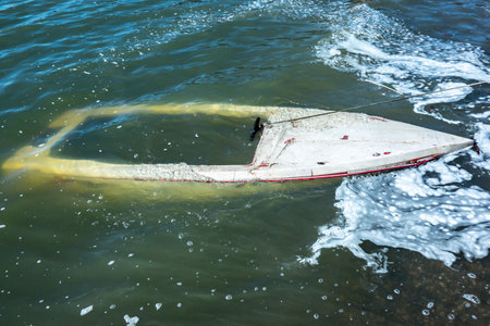 Sunken boat near the shore full of water and sea foamの写真素材