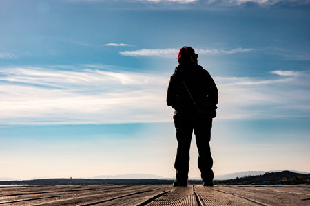 A woman posing on a pier by a lake meditating while looking at the world around herの写真素材
