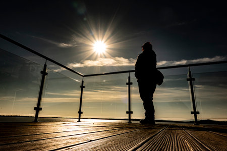 A woman posing on a pier by a lake meditating while looking at the world around herの写真素材