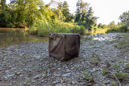 Old abandoned chair on the gravel beach by the riverの写真素材