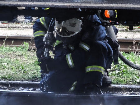 A fireman extinguishes a fire under a train chassis on a rail