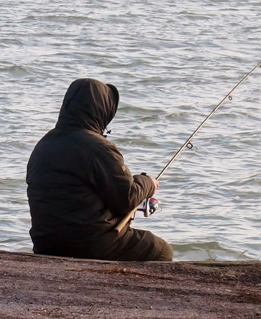 A lone fisherman fishing in a harborの写真素材