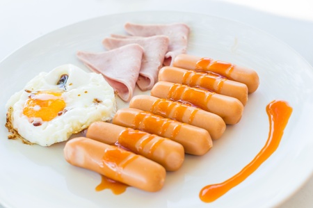 Wonderful breakfast.Sausage, ham and fried egg placed on a white dish.の写真素材