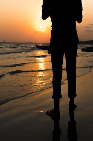 A black silhouette of a man standing  at the sunrise at the beachの写真素材