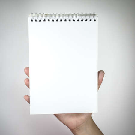 Woman hand holding white blank notebook.