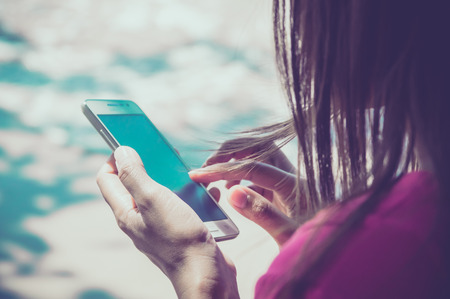 Woman using her Mobile Phone.on the beach Background.の写真素材