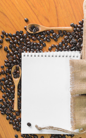 White notebook for your text with sackcloth and coffee beans on wooden spoon.の写真素材
