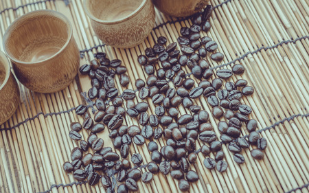 Coffee beans and coffee cup set on bamboo wooden background.Photo in retro color image style, Soft focus.の写真素材