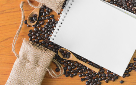 White notebook for your text with sackcloth and coffee beans on wooden spoon.の写真素材