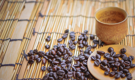 Photo in vintage color image style.Coffee beans and coffee cup set on bamboo wooden background.Soft focus.の写真素材