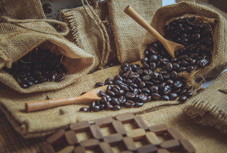Vintage photo of Coffee beans and wooden spoon on sack surface.の写真素材