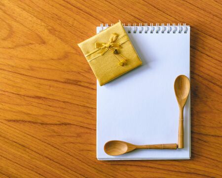 Gold ribbon bow and wooden spoon on blank notepad.の写真素材
