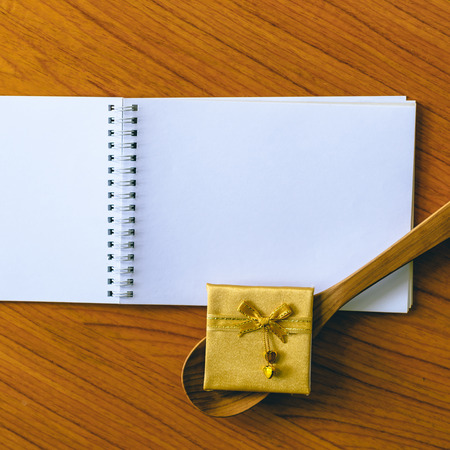 Gold ribbon bow and wooden spoon on blank notepad.の写真素材