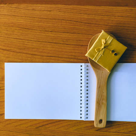Gold ribbon bow and wooden spoon on blank notepad.の写真素材