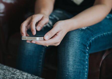 Vintage photo of woman using mobile smart phone in coffee shop.Close up female student reading text messages on her mobile phone.の写真素材